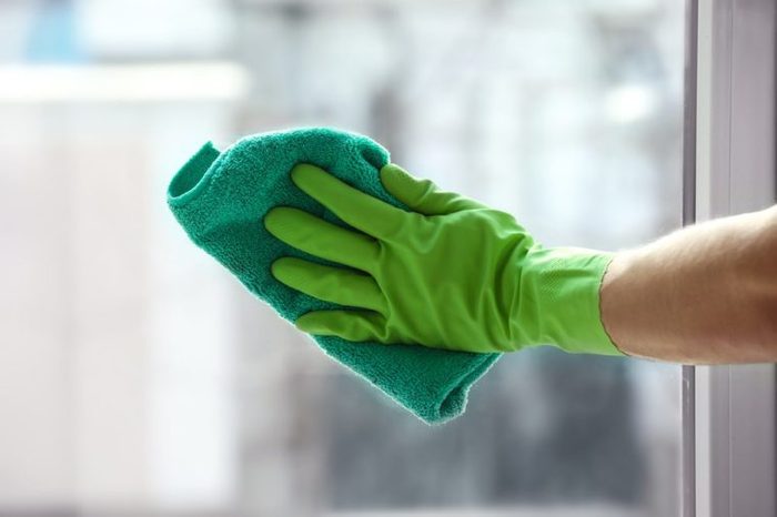 Hand of young man cleaning window in office
