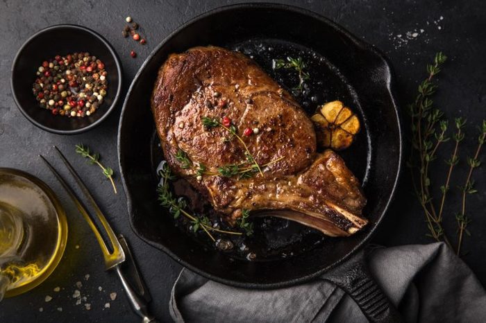 beef steak on cast iron pan, dark background, top view
