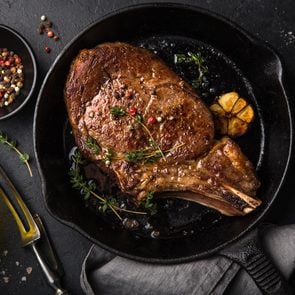 beef steak on cast iron pan, dark background, top view
