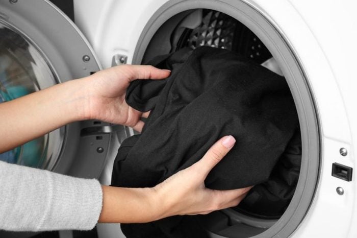 Female hands getting out clean clothes from washing machine