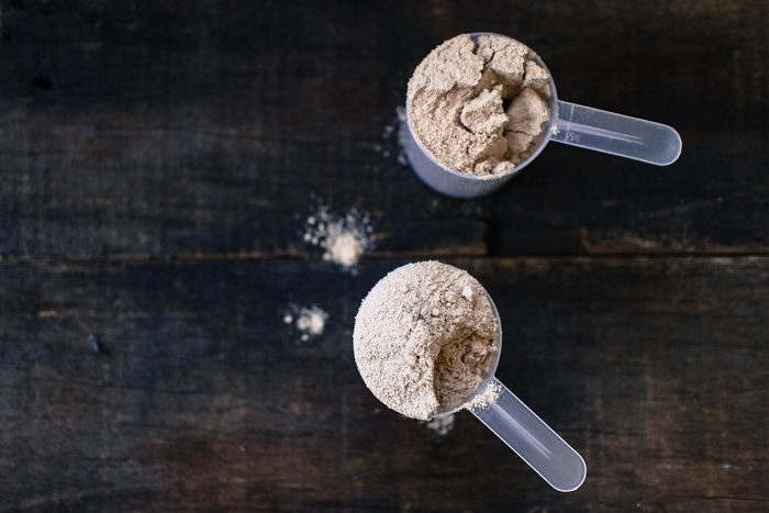 Foods everyone over 50 should be eating - Whey powder in measuring scoops on wooden background.