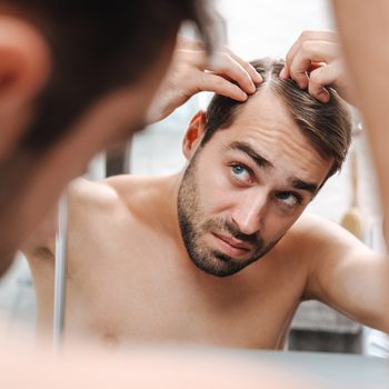 Signs you're not eating enough protein - man checking hair loss in mirror