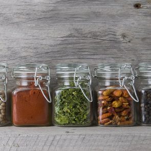 Glass jars with some spices on an old wooden stand.