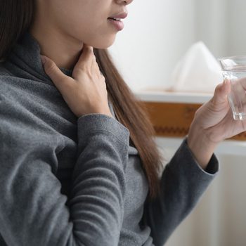 Strep throat signs to never ignore - Woman touching her throat