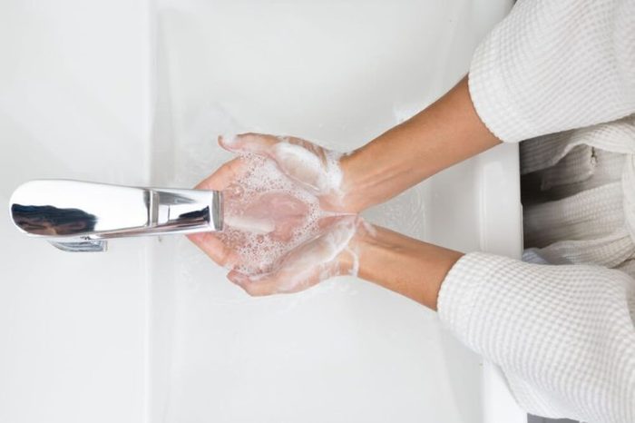 Woman in a bathrobe is washing hands.