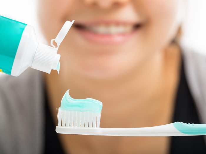 How long you should brush your teeth for - woman squeezing toothpaste onto toothbrush