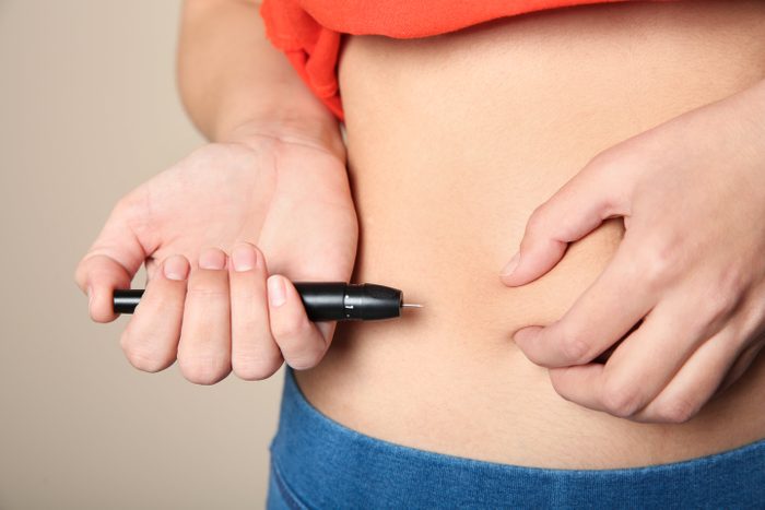 Woman doing insulin injection in stomach, closeup. Diabetes disease