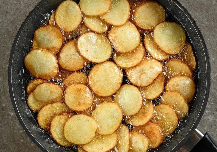 frying potatoes in pan with oil, top view