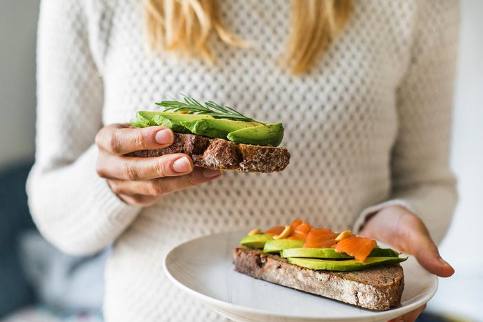 How to live to 100 - close up of woman holding plate with avocado toast as fresh snack, day light.