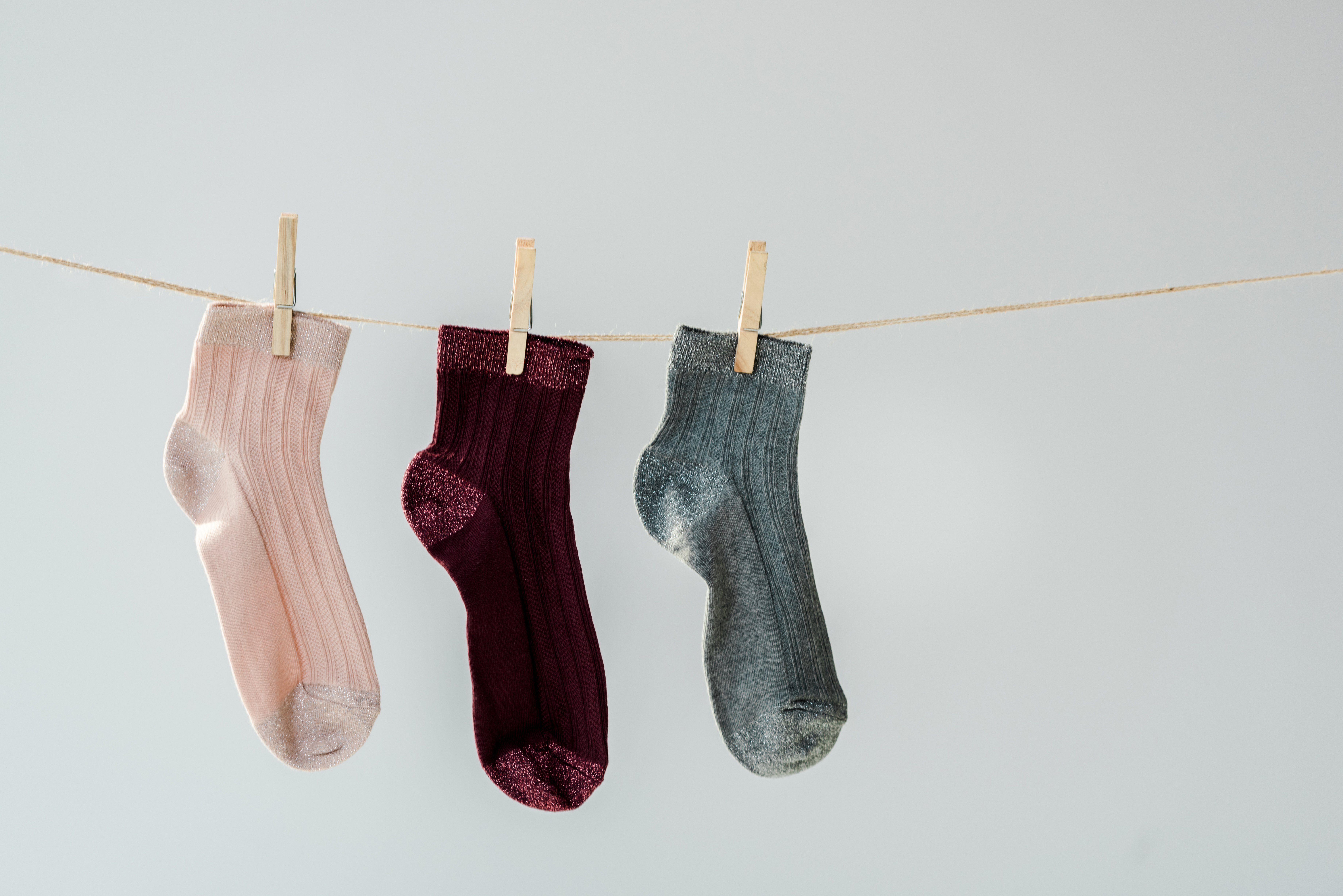 close up of multicolored shiny socks hanging on clothesline isolated on grey