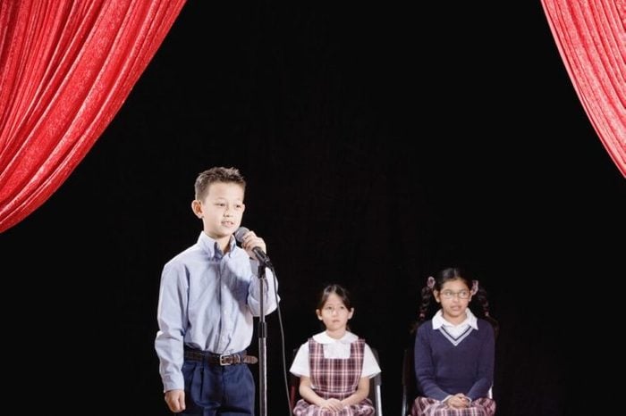 Asian boy speaking into microphone on stage