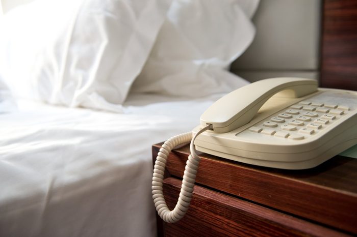 Phone on a table near a bed.