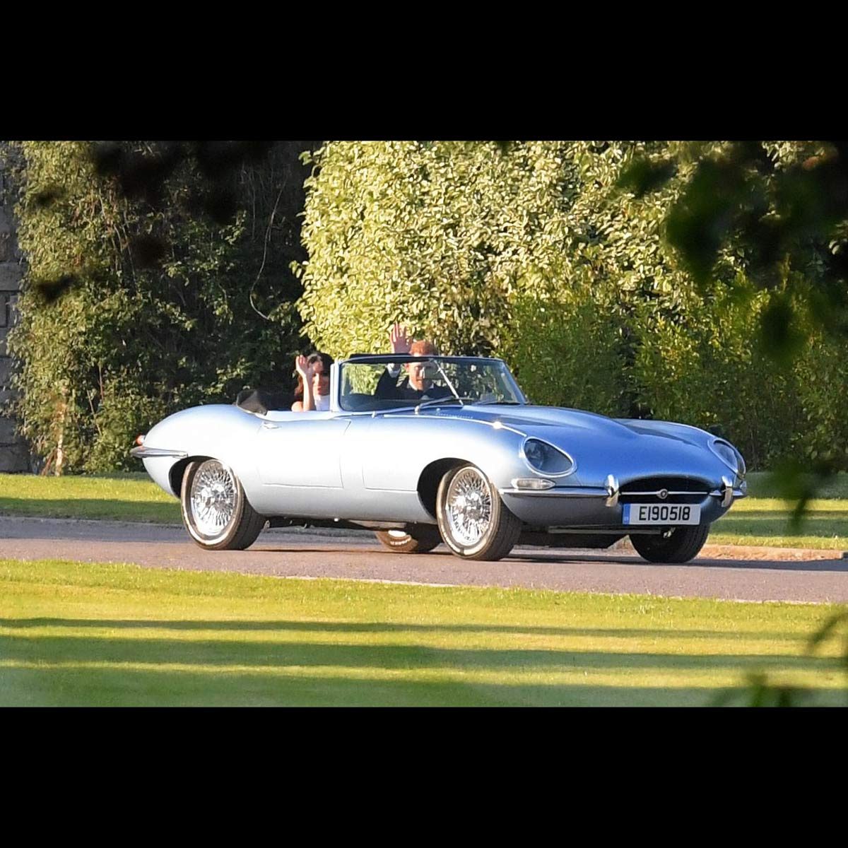 Prince Harry and Meghan Markle wave as they drive away in a Jaguar E-type following their wedding