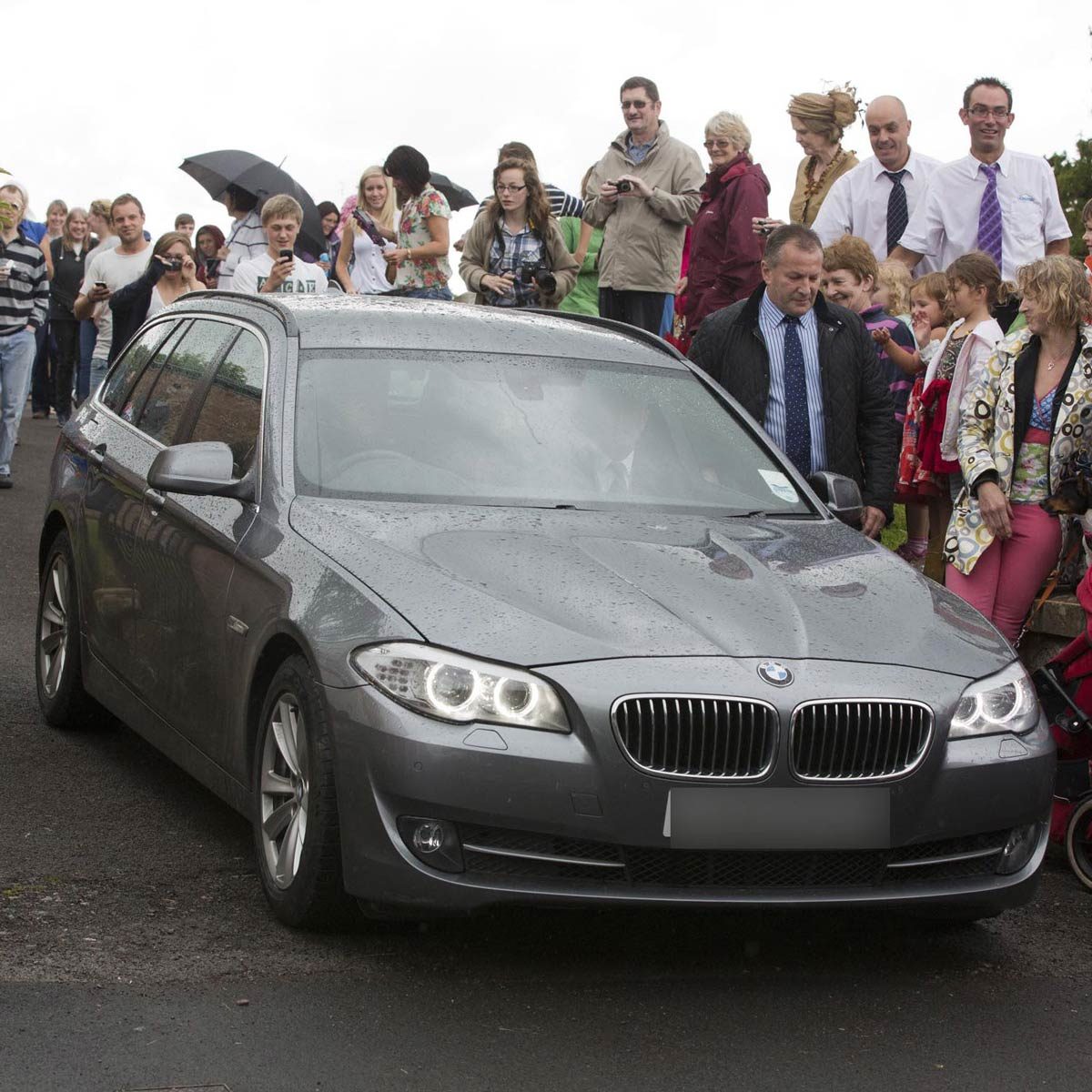Prince William and Catherine Duchess of Cambridge drive in a gray BMW wagon