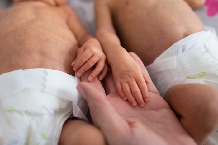 mother holding premature twins hands