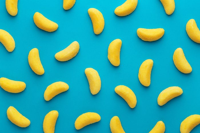 Banana shaped candy pattern on a blue background. Jelly candies viewed from above. Top view. Repetition concept
