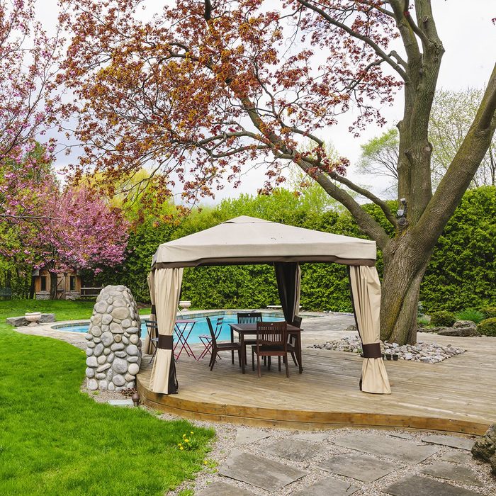 Residential backyard with gazebo, deck, stone patio and swimming pool