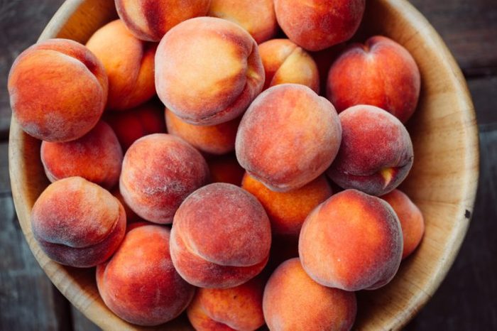 A group of ripe peaches in a bowl
