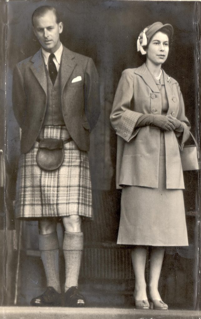 Queen Elizabeth & Duke Of Edinburgh - September 1952 Wearing Kilts - Duke Wears Balmoral Tartan .... The Queen Is In Grey And Her Hat Is Trimmed With Yellow Tassels; The Duke Of Edinburgh Wears The Mauve And Grey Balmoral Tartan. They Are Watching Th