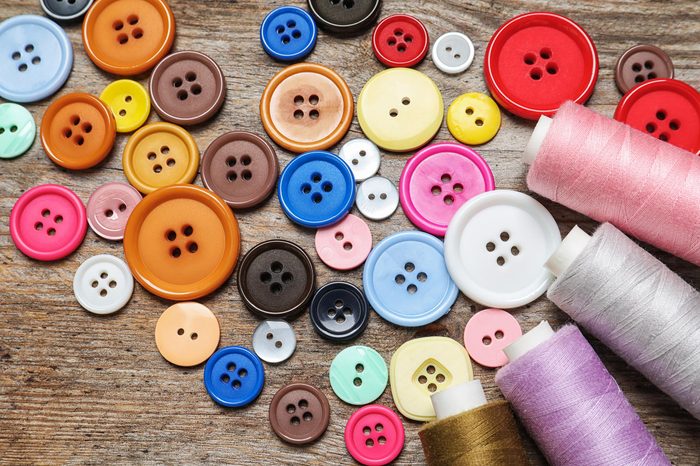 Colorful buttons and threads on wooden background, top view. Tailoring equipment