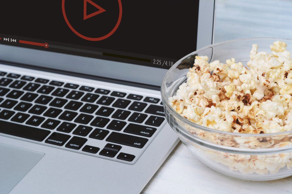 Popcorn in bowl and laptop playing movie. Entertainment concept