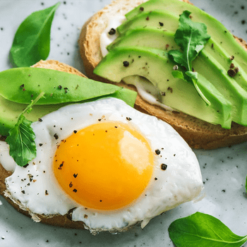 Avocado Sandwich with Fried Egg - sliced avocado and egg on toasted bread with arugula for healthy breakfast or snack.