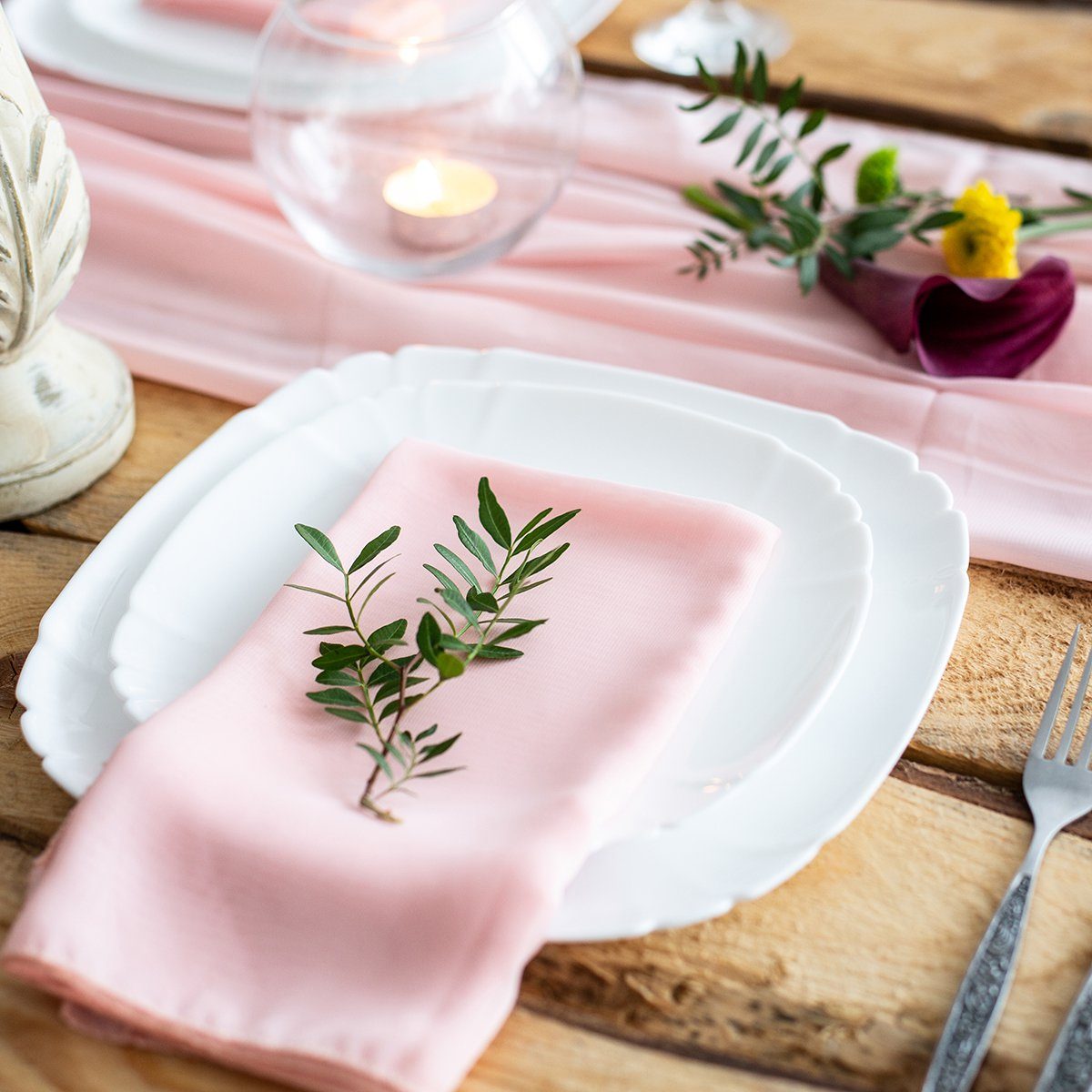 Rustic table setting: pink napkin folded on a plate, next to a champagne glass