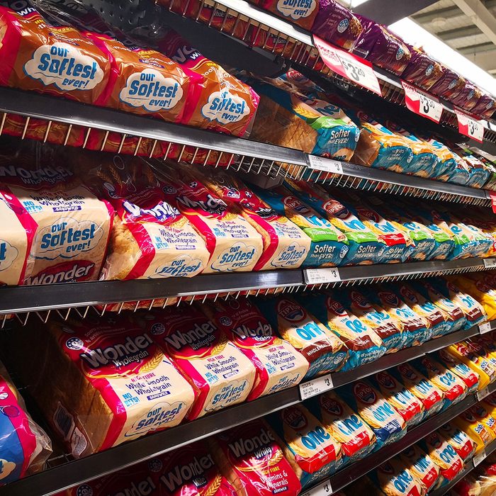 Interior view of Woolworths store shelf with bags of various brand breads.