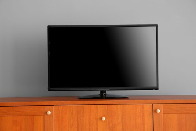 what do burglars want - wide screen TV on wooden commode near grey wall