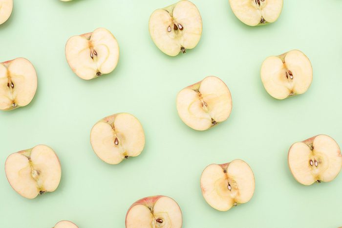 Background of cut in half apples on green background. Top view