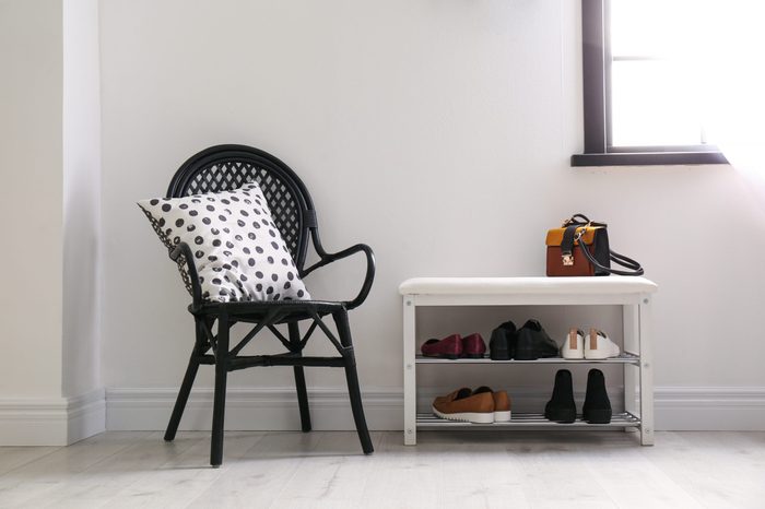 Collection of stylish shoes on rack storage near white wall in room