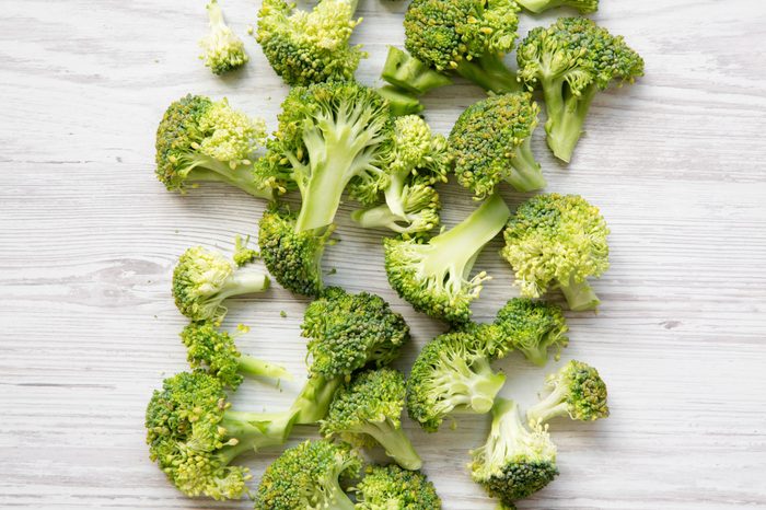 Freshly cut raw broccoli on white wooden surface, overhead view. Flat lay, from above.