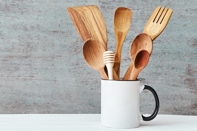 Kitchen utensils in ceramic cup on gray background, copy space