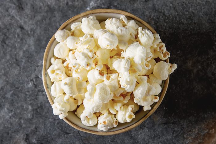 Salted popcorn in a cup. Dark background. Selective focus. Fast food for movies