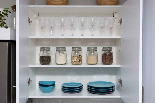 Various seeds in storage jars in pantry, white modern kitchen in background. Smart kitchen organization