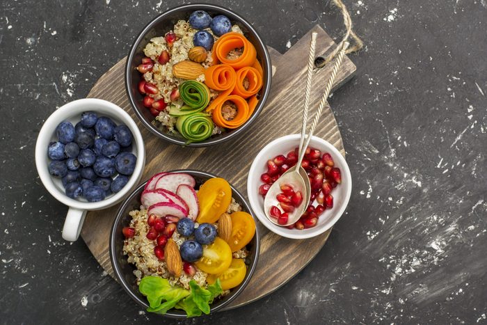 Foods not to avoid - Vegetarian Quinoa bowl. Healthy breakfast or snack with detox quinoa, tomato, cucumber, carrot, pomegranate seeds, juicy blueberries and lettuce in portioned bowls. Top