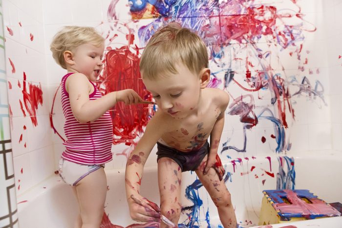 Portrait of two cute adorable white Caucasian little boy and girl playing painting on walls in bathroom, having fun, lifestyle active childhood concept, early education development
