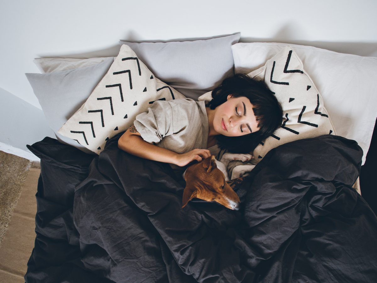 Health studies - woman sleeping in bed with her pet dog