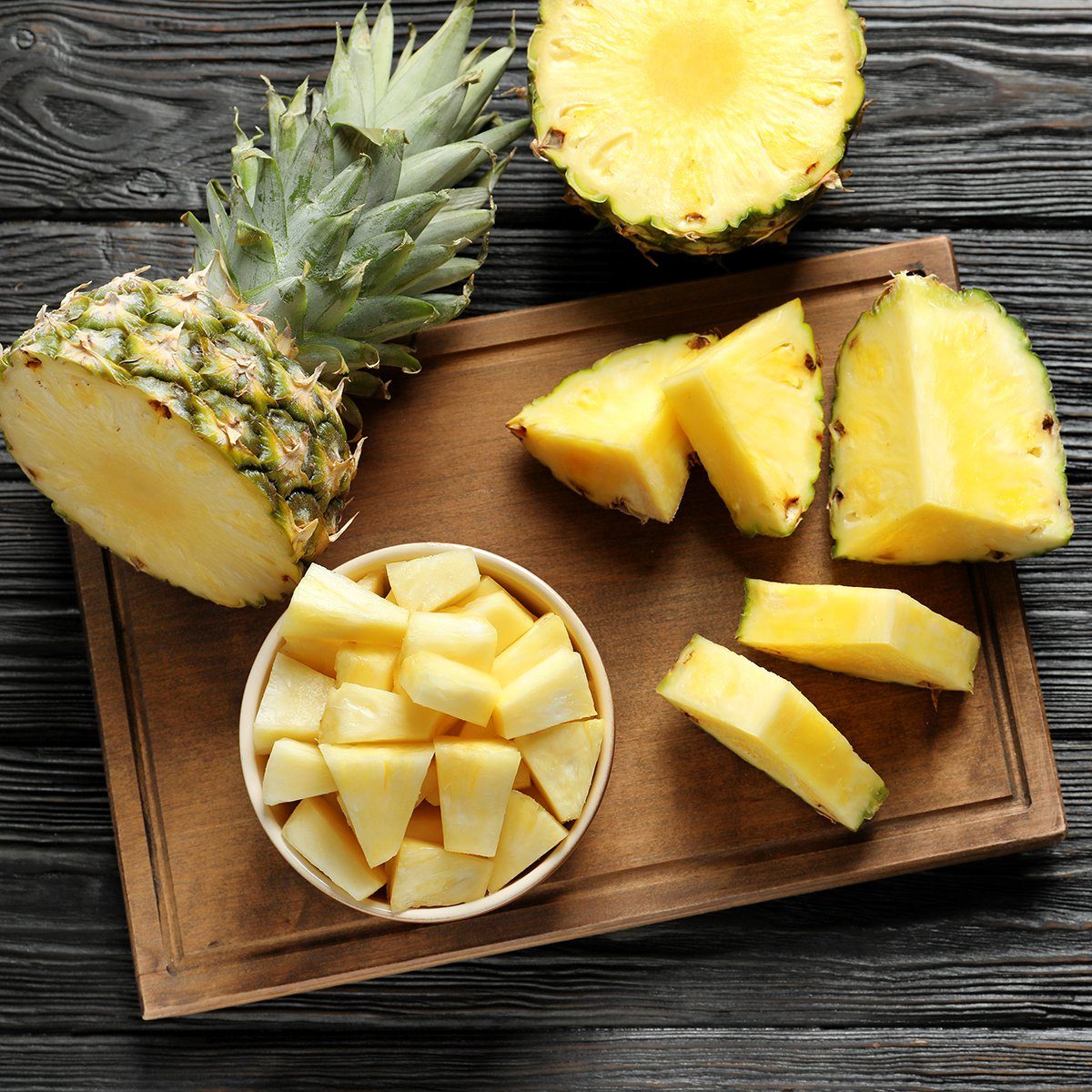 Wooden board with fresh sliced pineapple on table