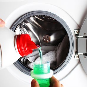 Pouring laundry detergent into washer
