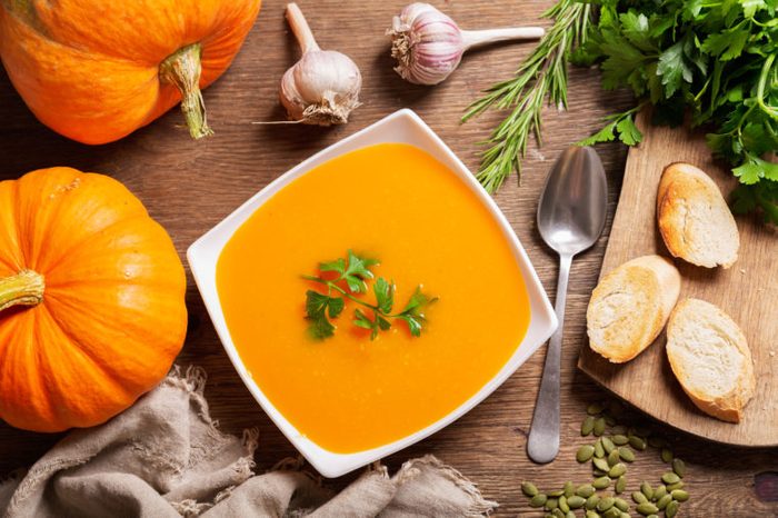 bowl of pumpkin soup with ingredients for cooking, top view