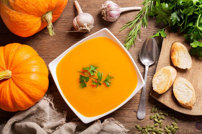 bowl of pumpkin soup with ingredients for cooking, top view