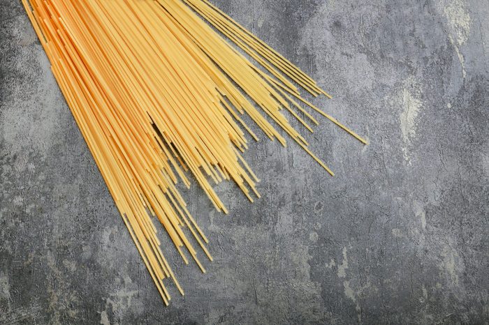 Spaghetti pasta on grey stone background, copy space.