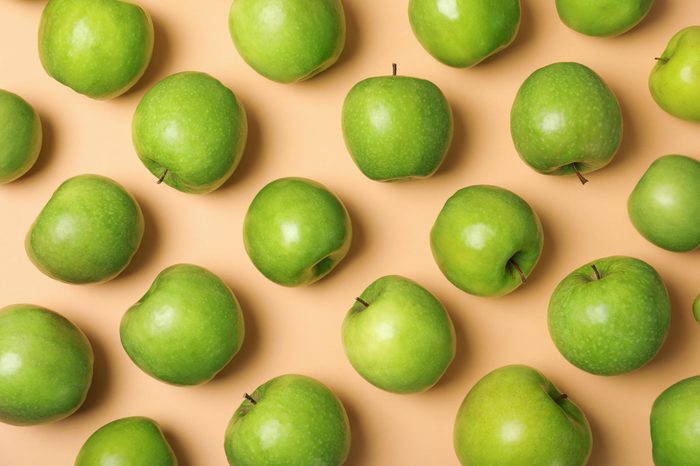Many juicy green apples on color background, top view
