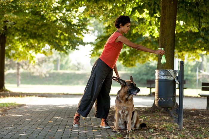 Woman is throwing away the poo of her dog