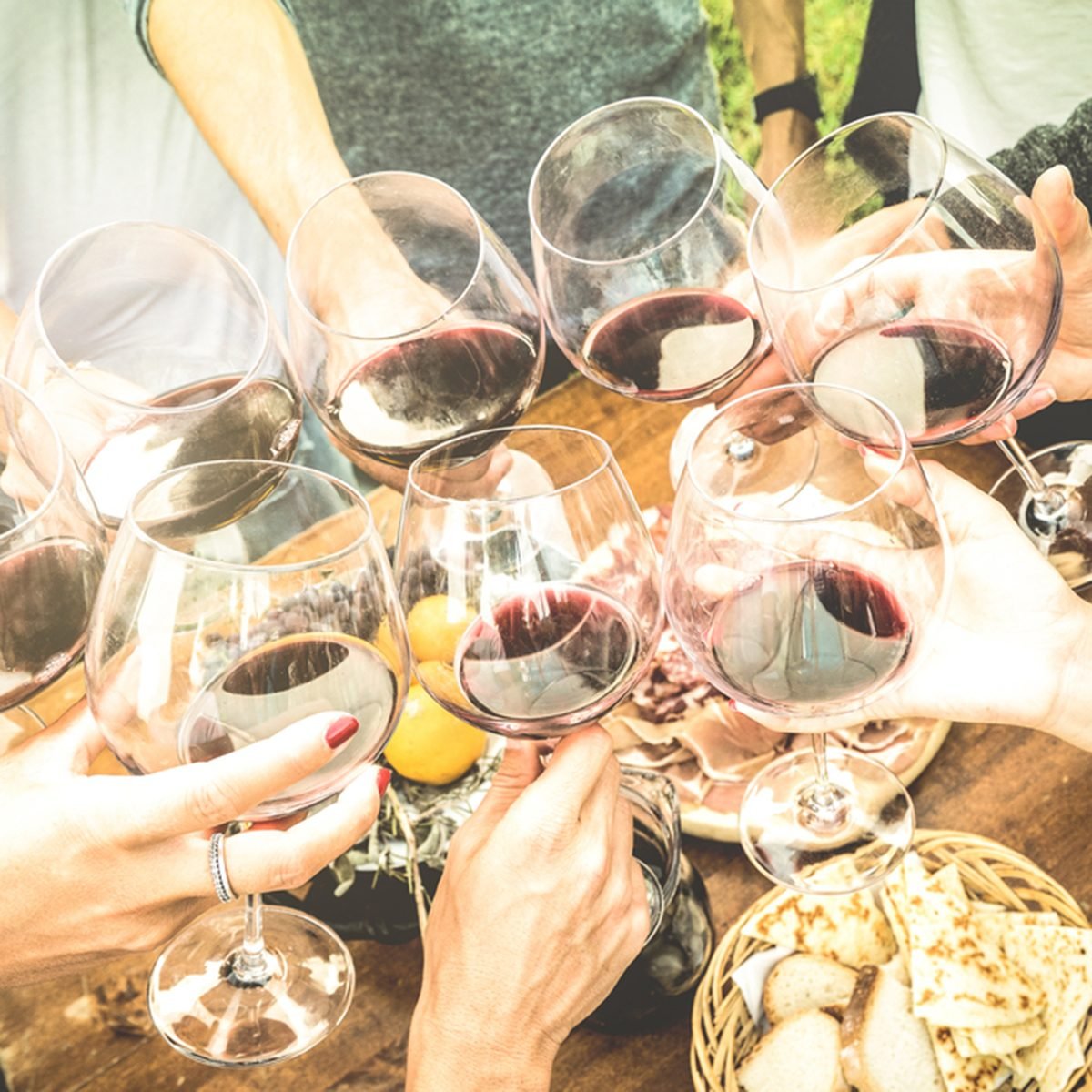 Friends hands toasting red wine glass and having fun outdoors cheering with winetasting - Young people enjoying harvest time together at farmhouse vineyard countryside - Youth and friendship concept; Shutterstock ID 570070135