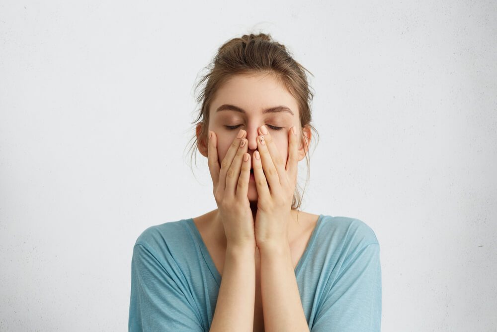Stressed or tired woman with hands on her face 