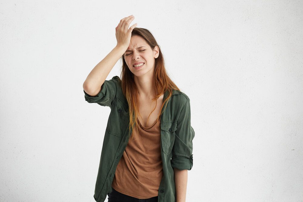 signs of high-functioning anxiety - Stressed woman with hand on head, looking frustrated