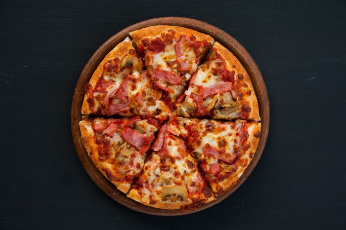Slices of pizza on rustic wooden tray and dark background