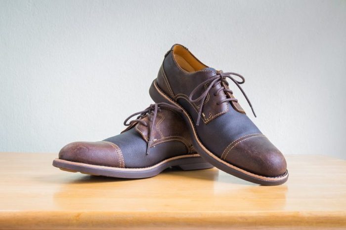 Men's accessories with brown leather shoes on wooden table, bar or counter over gray wall background